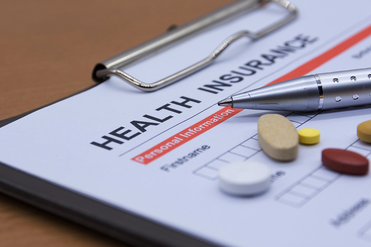 Image of a clipboard with a pen and paper, displaying the words 'Health Insurance'.