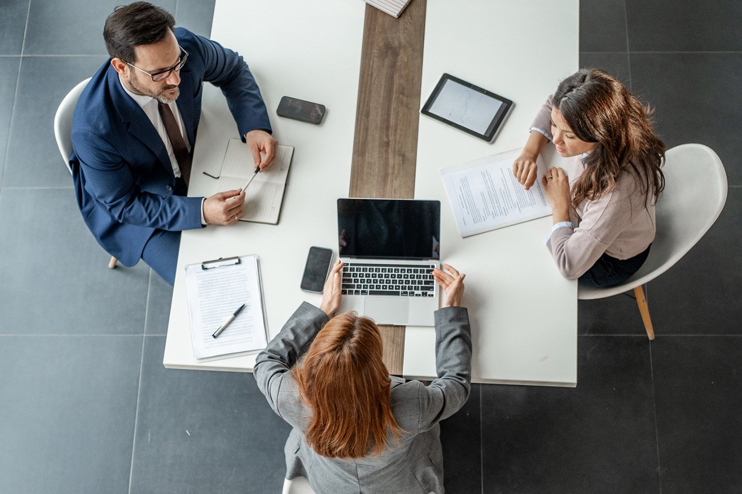 A bird's eye view of a conference table with coworkers collaborating, showcasing teamwork and professional synergy.