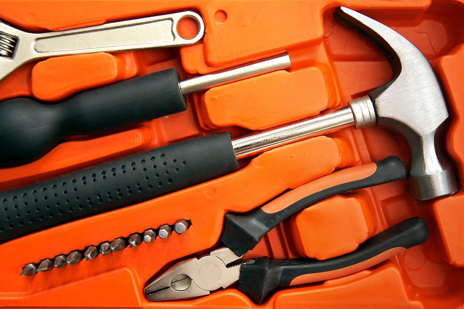 An orange tool kit filled with various essential tools for home improvement, including hammers, screwdrivers, and pliers, against a backdrop of a leading home improvement retailer. 