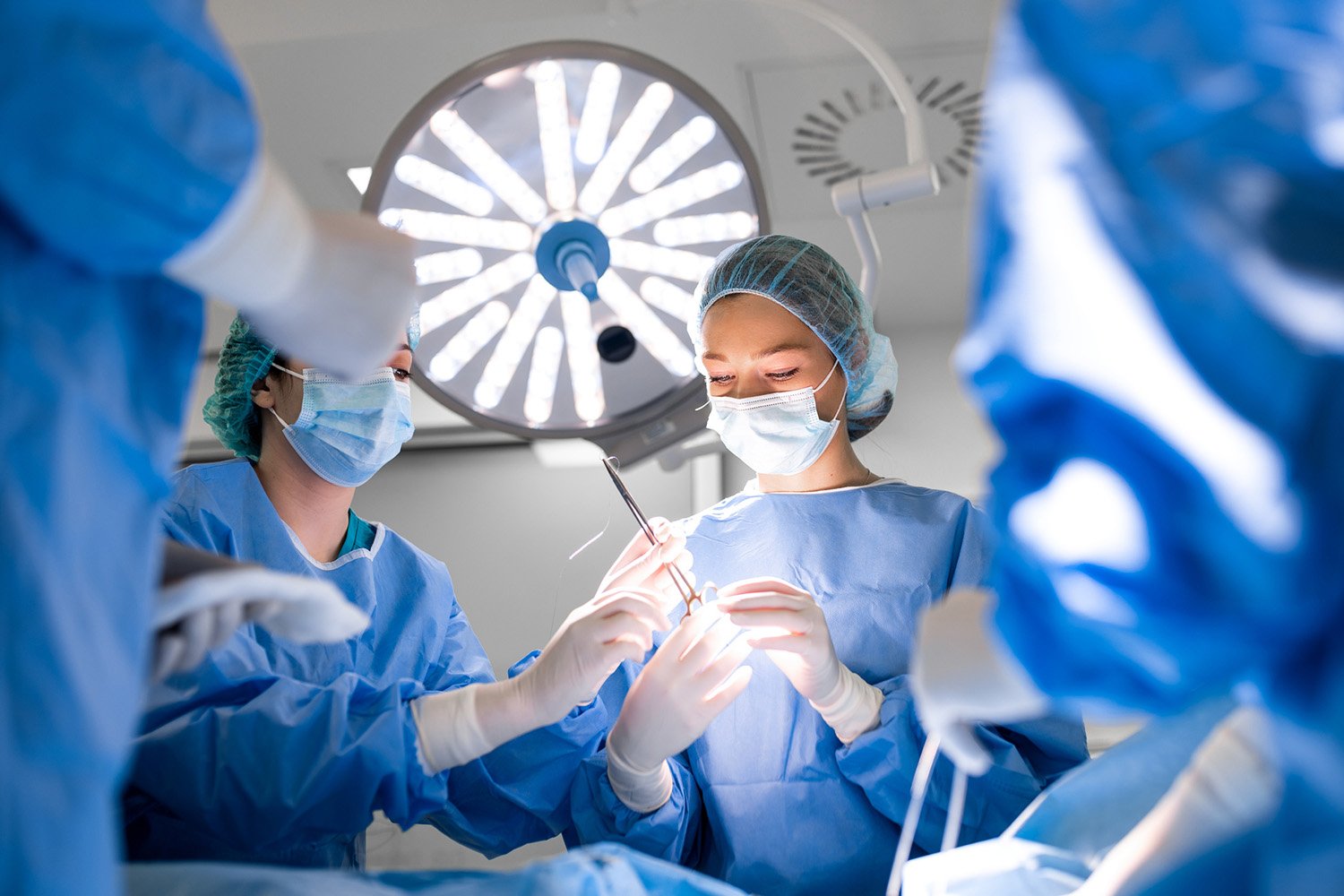 Image of female surgeons performing surgery in a high-tech operating room, representing a multinational healthcare services company.