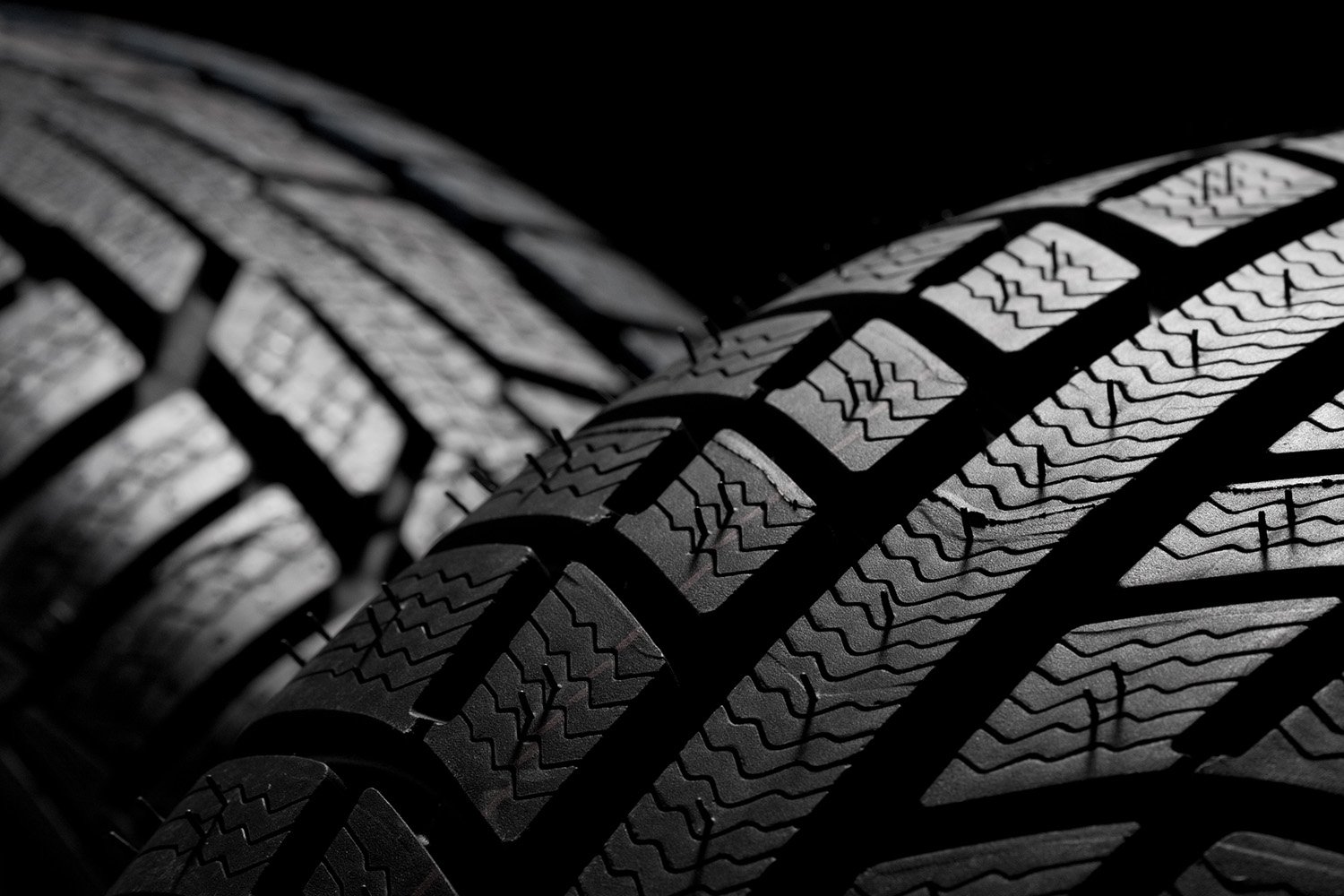 Two automotive tires against a black background, highlighting the intricate tread patterns.