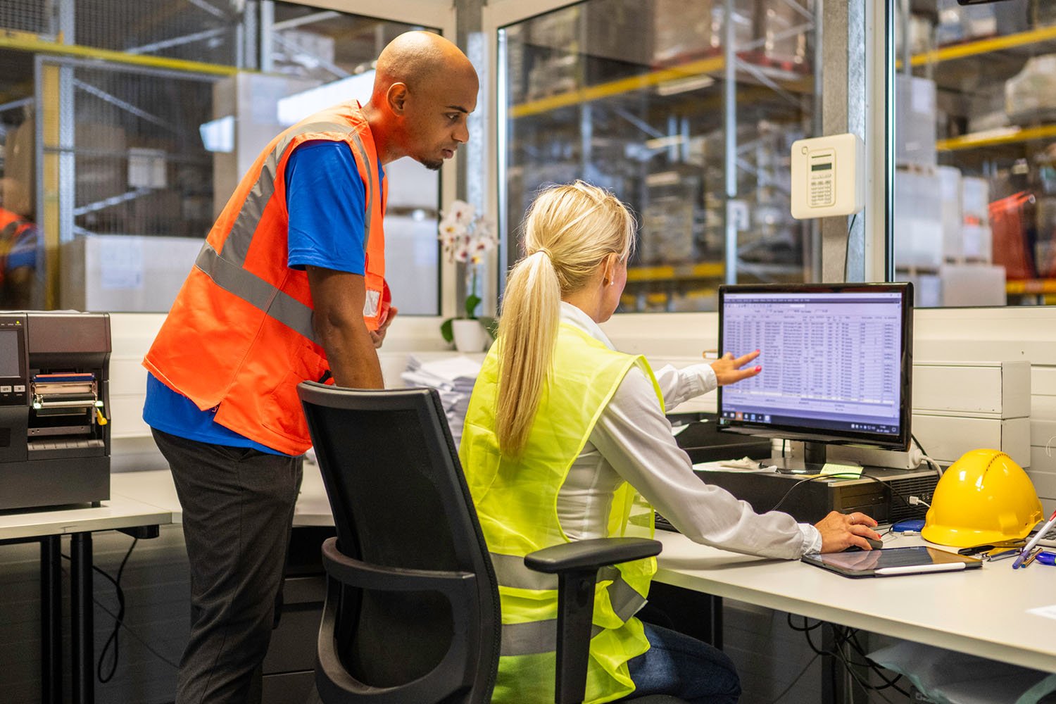 Two professionals in safety vests reviewing data