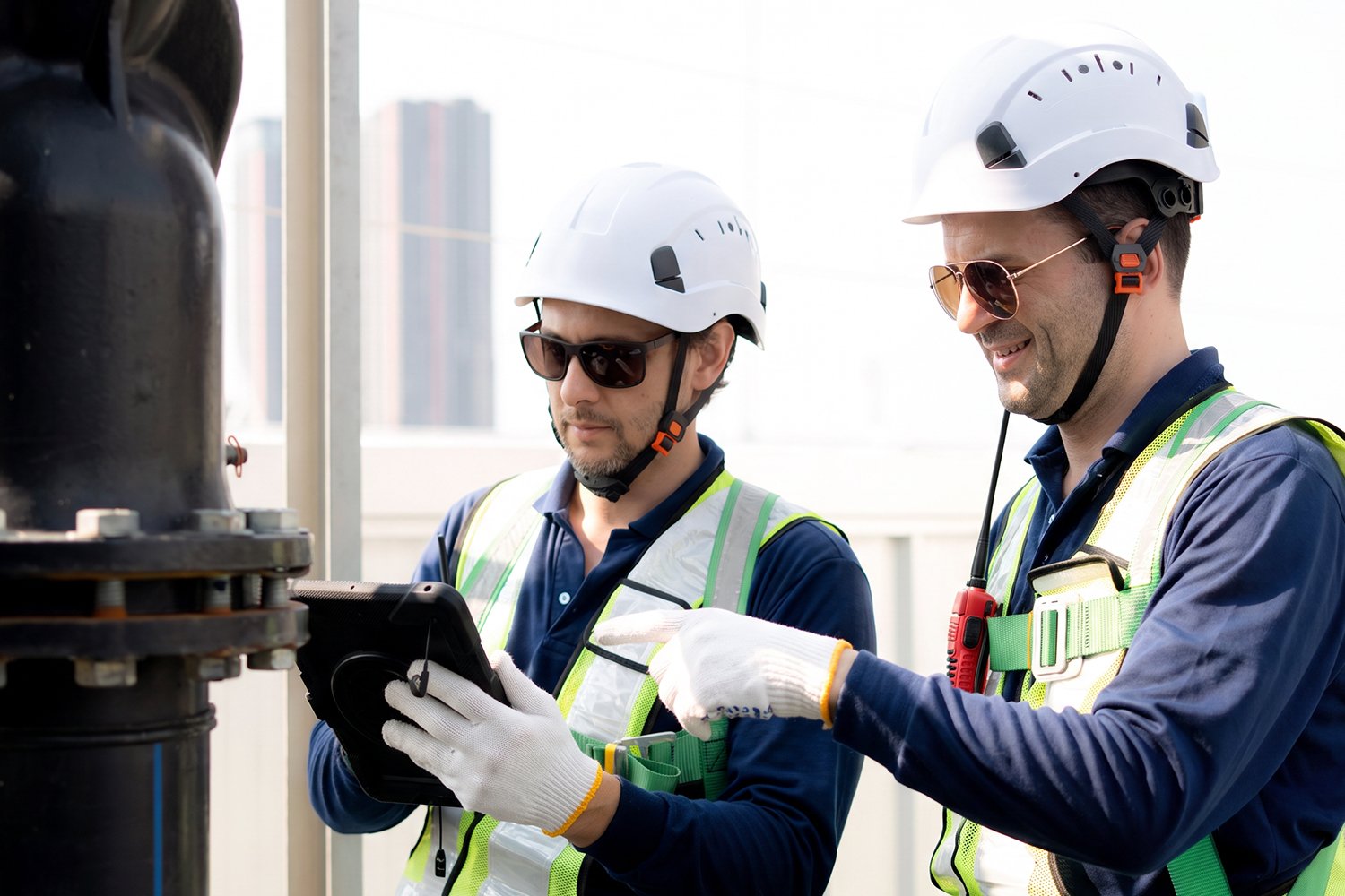 Two utilities workers in safety gear working using a tablet