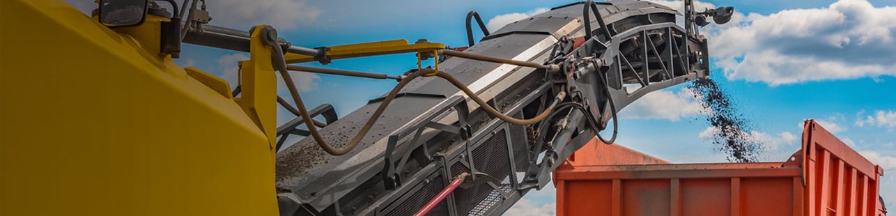 Equipment dumping asphalt into a truck