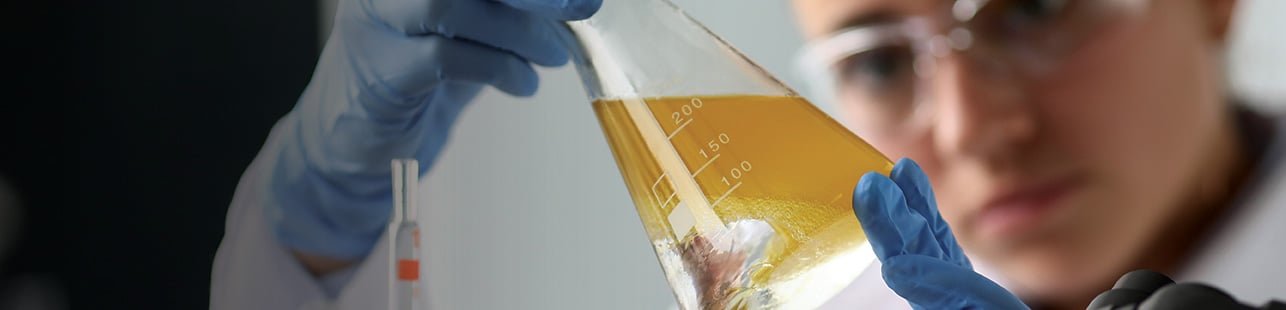 Scientist looking at fluids in beaker