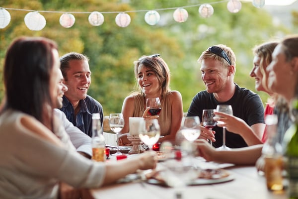 7 mennesker om et bord, der spiser middag udenfor