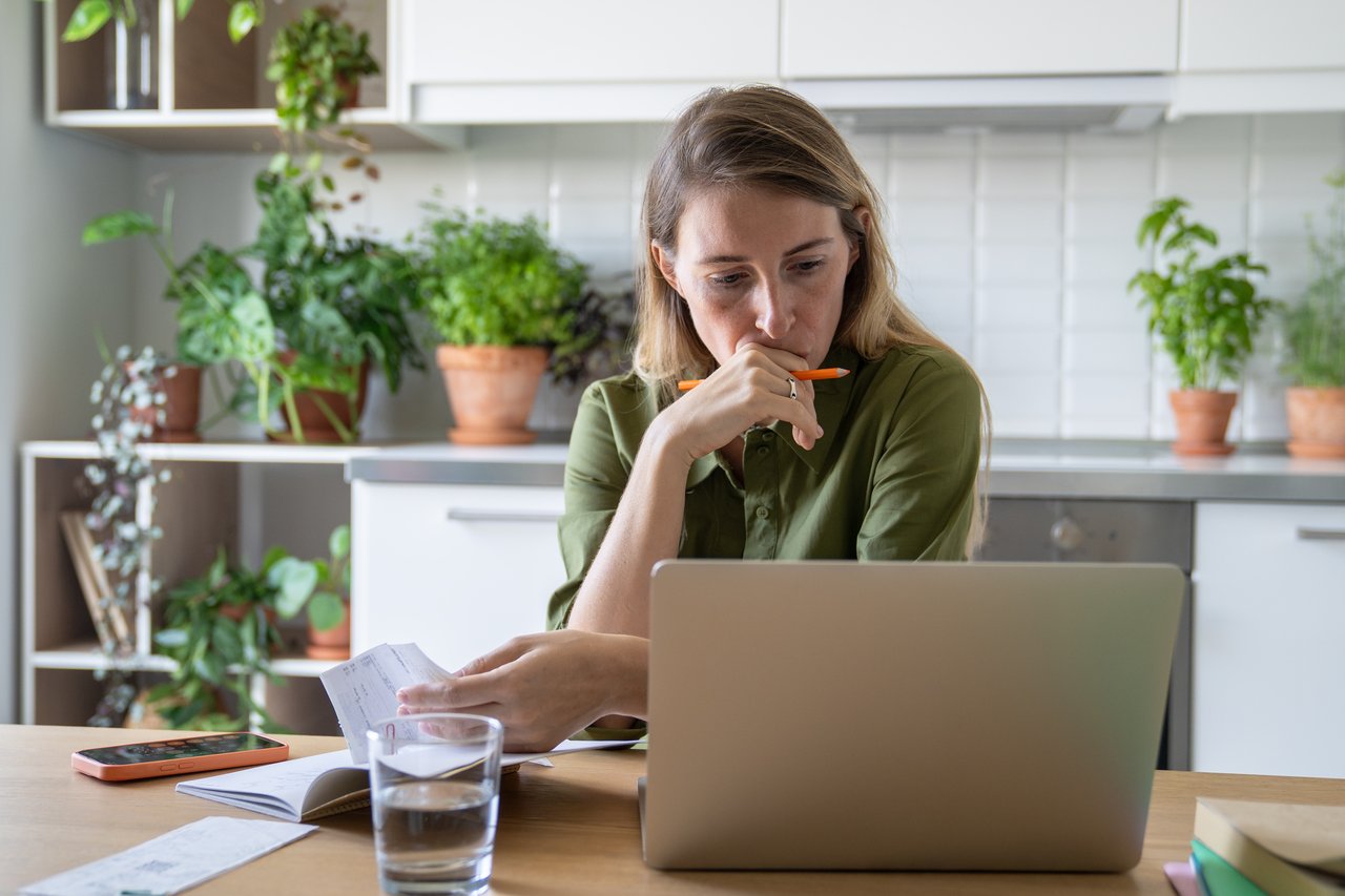 Dame sidder ved computeren med en kuglepind