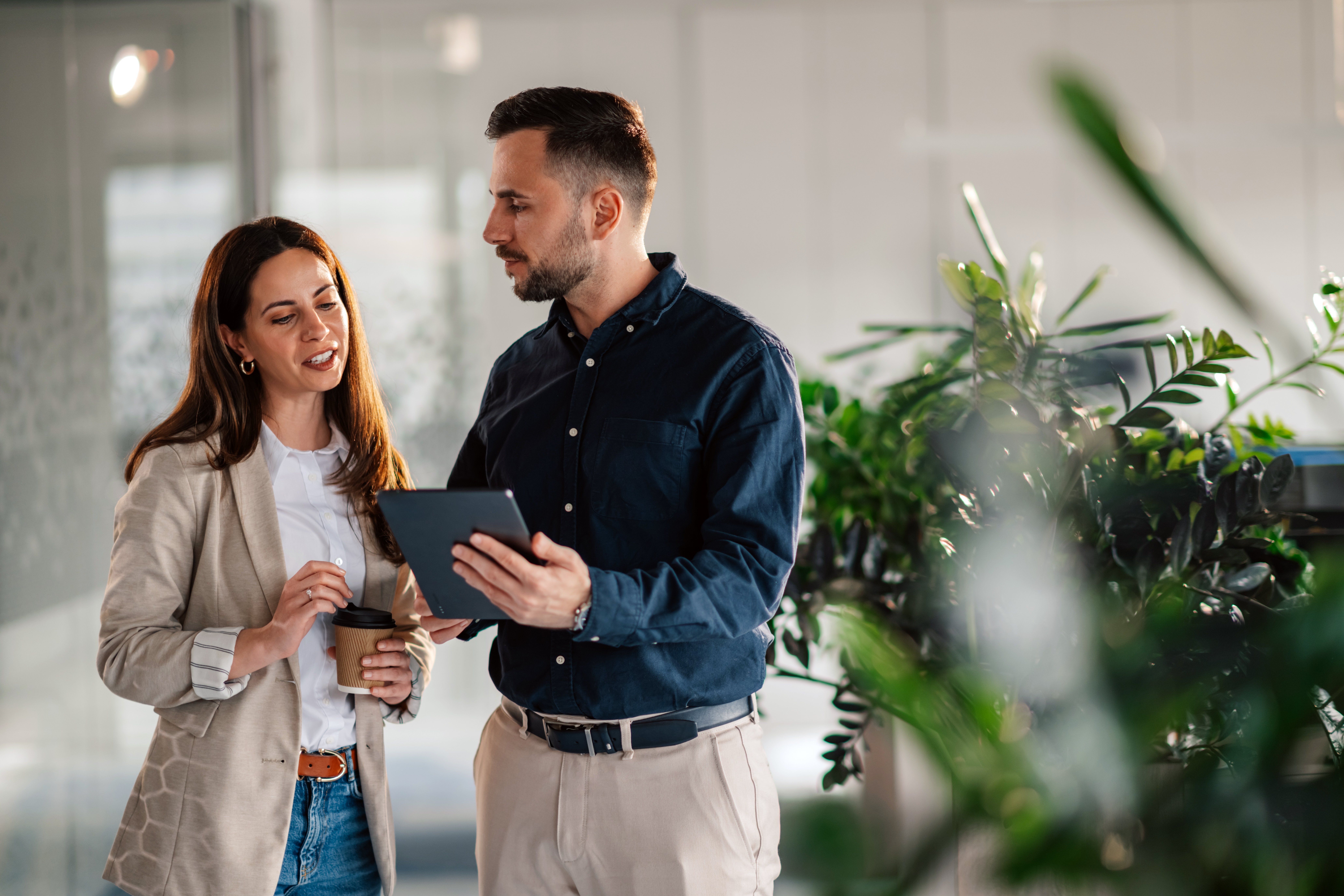 Mand med tablet i hånden snakker med dame på arbejdet 