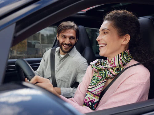 two customers laughing in a Porsche