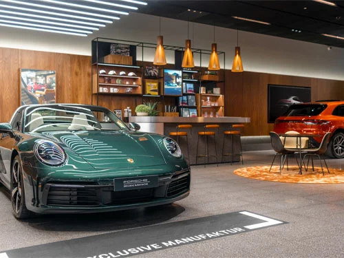 Green Porsche Targa in a studio space with a Orange Macan in the background