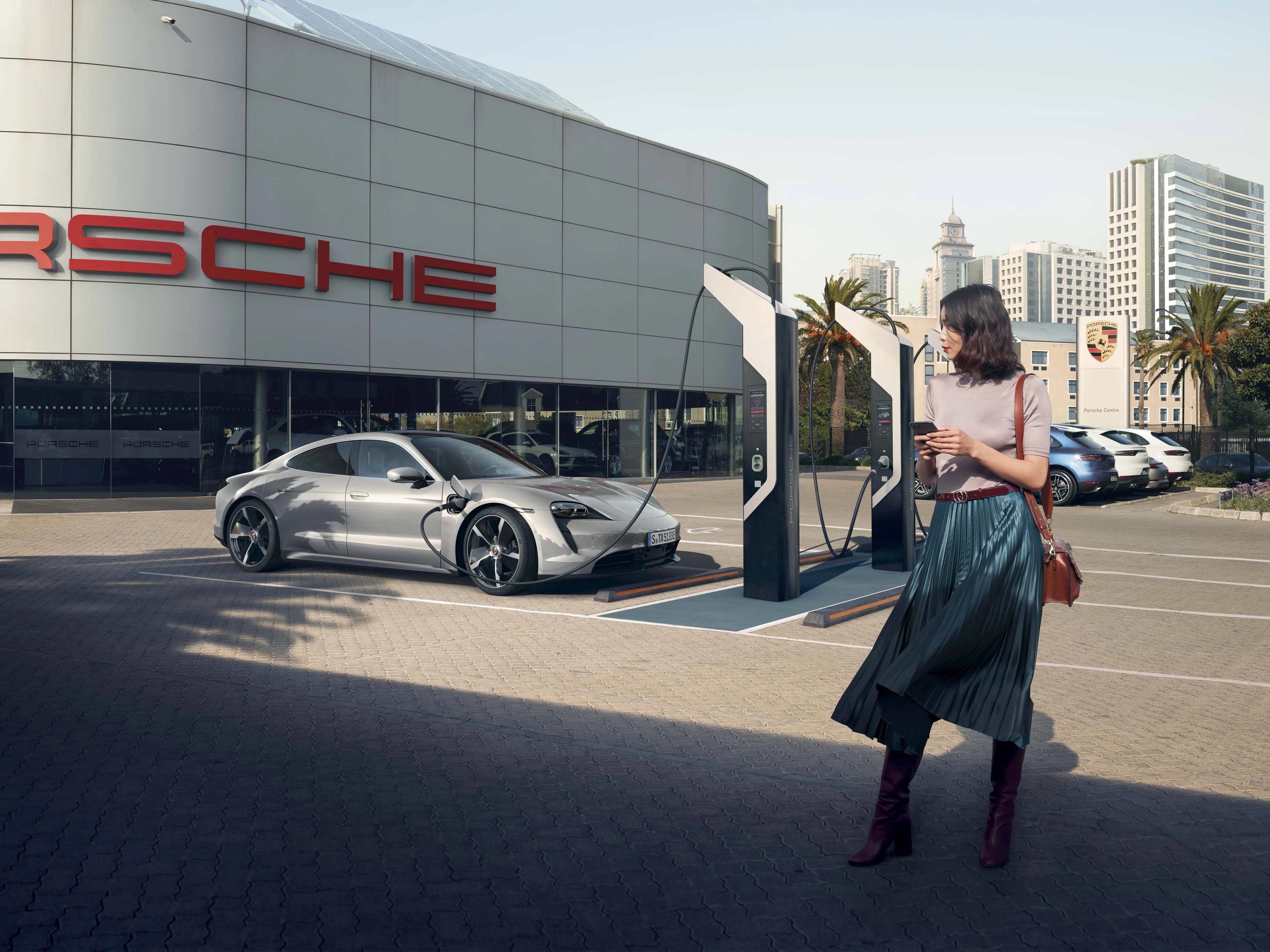 Porsche Taycan på laddning utanför ett Porsche Center