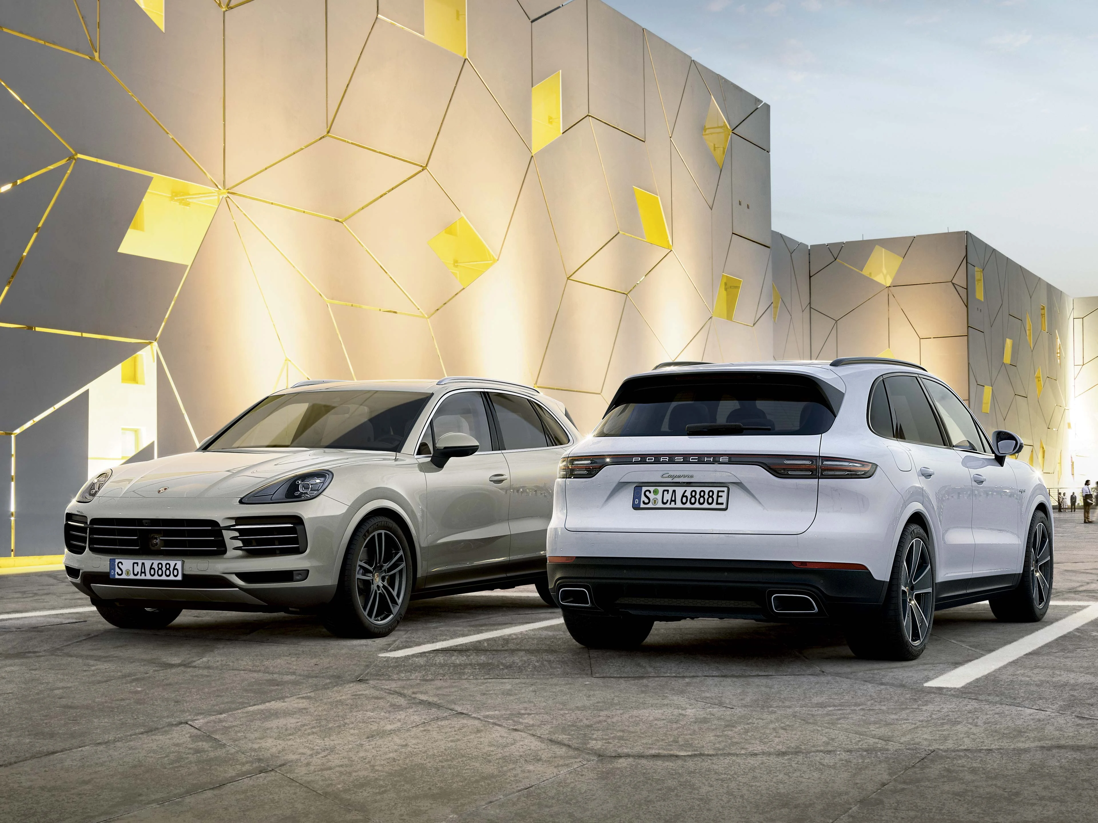 Två Porsche Cayenne med dramatisk arkitektur i bakgrunden