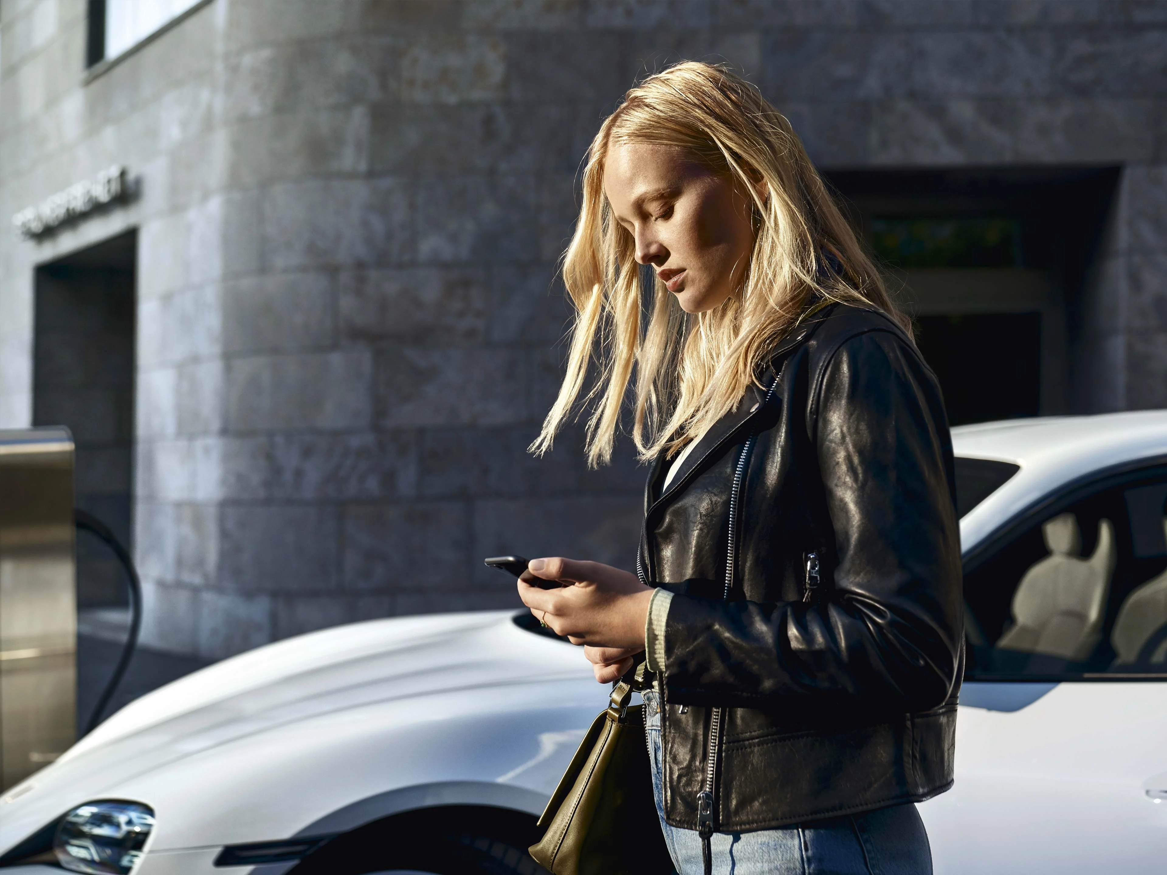 Porsche Connect: Kvinna med smartphone vid en vit Porsche