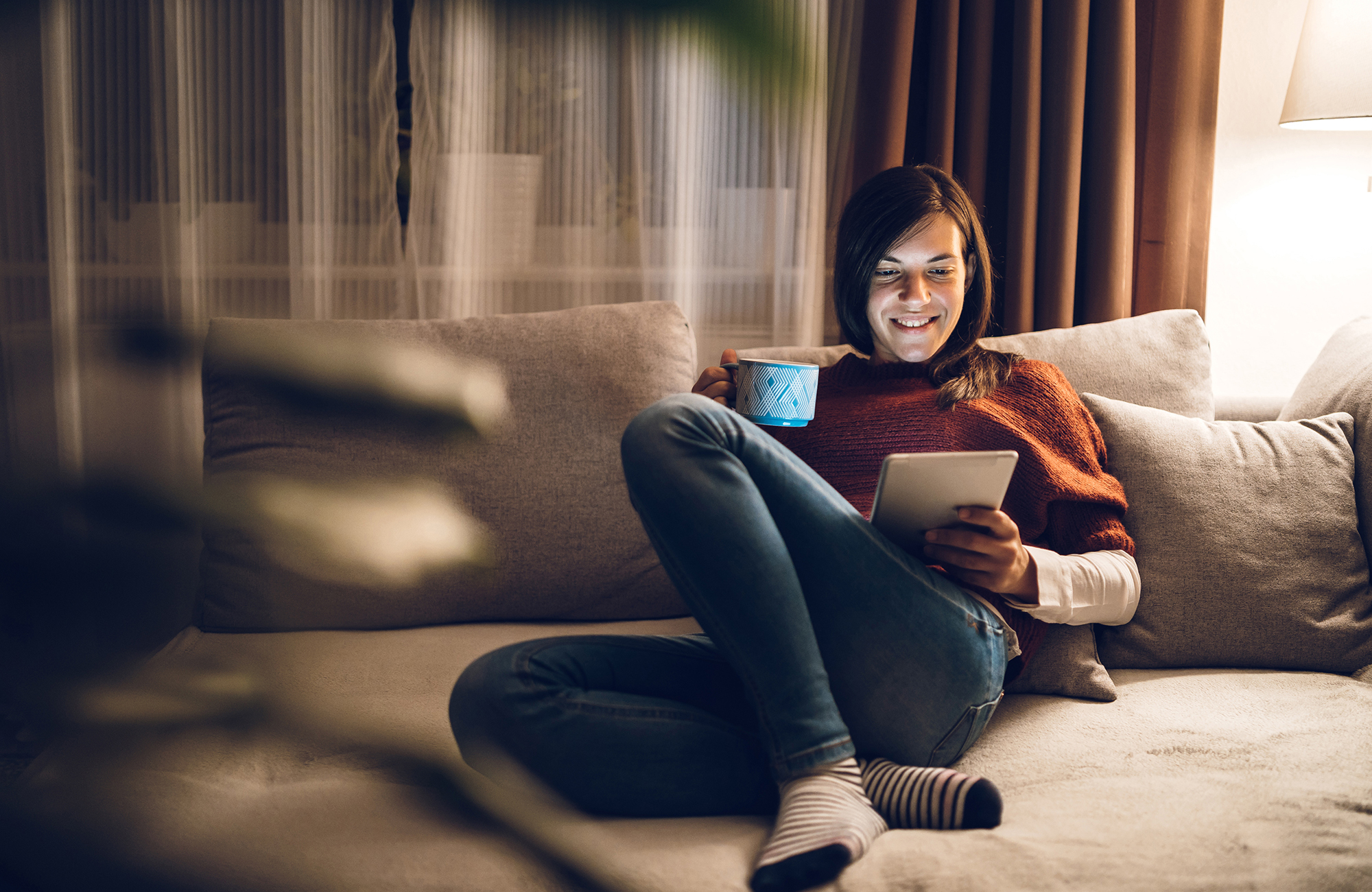Woman on a couch with a tablet and coffee