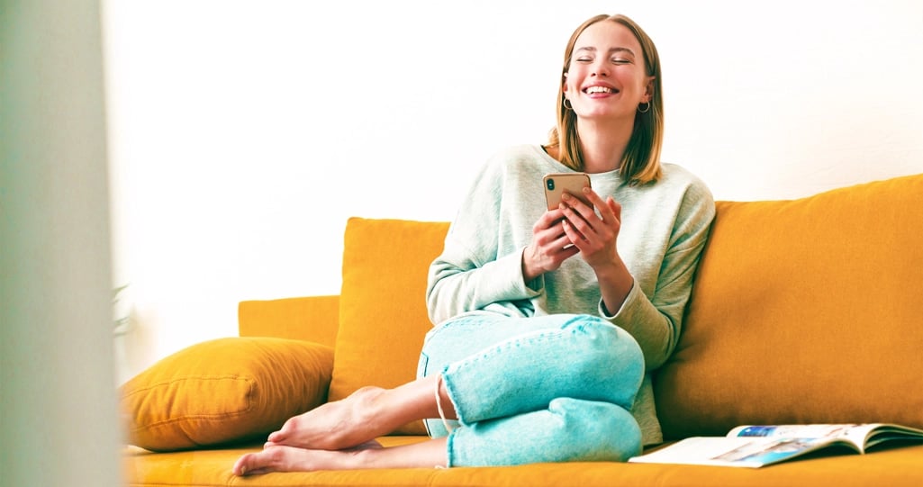 Vrouw op bank met telefoon in de hand