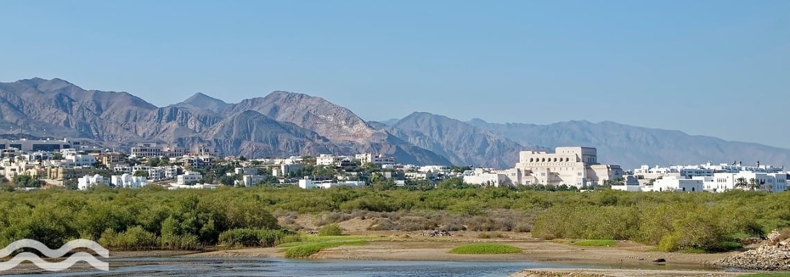 A photo of water in a field with Muscat Oman in the distance