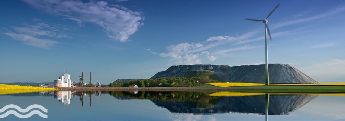 Water in front of a potassium salt mine with renewable energy turbine on the lake shore