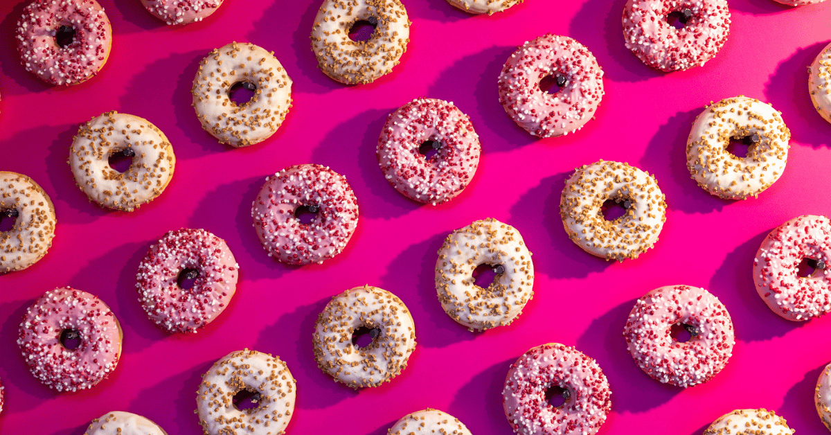 Roze en witte donuts met sprinkles op een felroze achtergrond