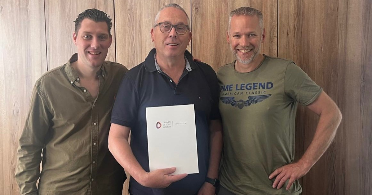 Drie mannen staan lachend naast elkaar met een certificaat