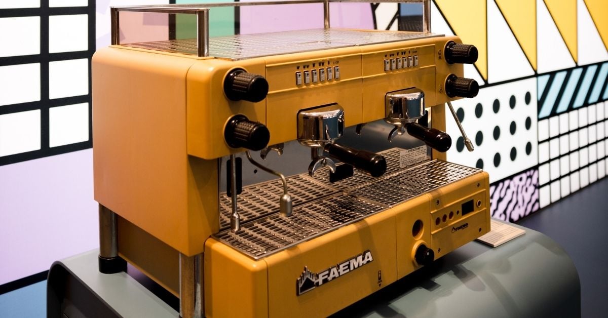 een geel koffie apparaat van faema met gekleurde muur op achtergrond