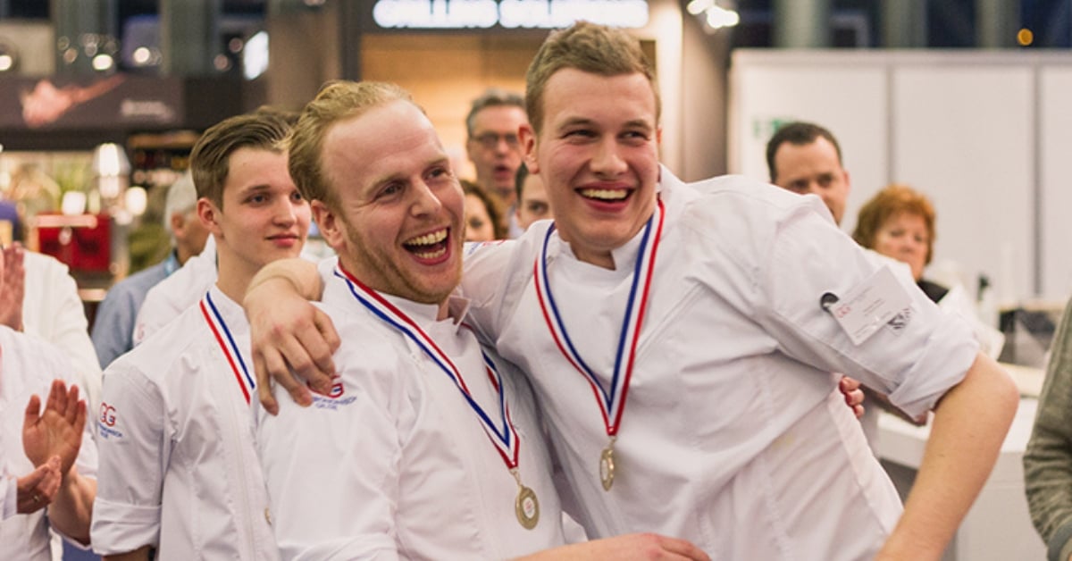 Twee blije chefs met medailles om de nek vieren hun overwinning op het NK Leermeester-Leerling tijdens Horecava