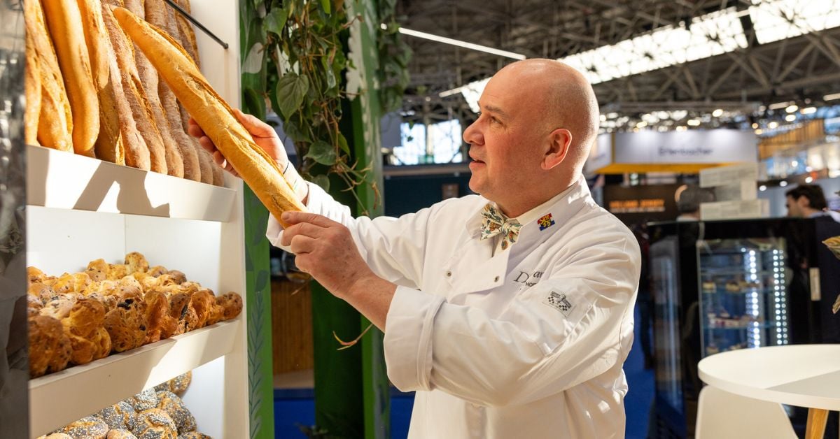 Een bakker bekijkt en selecteert een versgebakken baguette