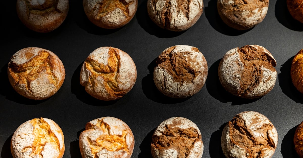 Ambachtelijke broodjes met krokante korst, vers gebakken en uitgelicht tegen een donkere achtergrond