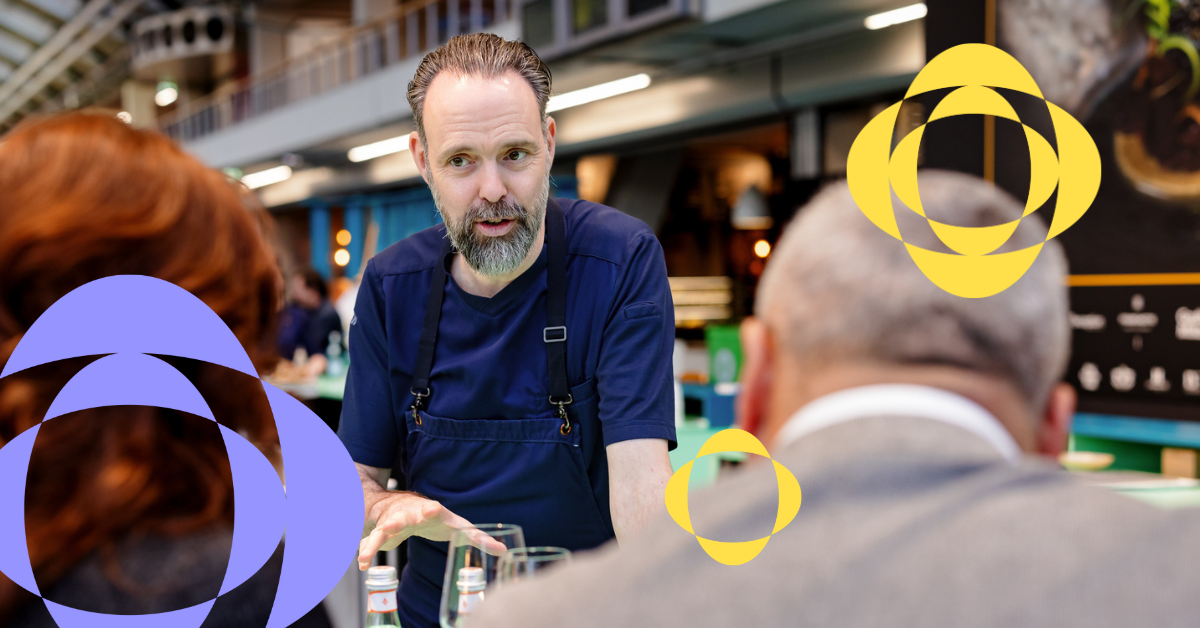 Chef in gesprek met twee bezoekers tijdens een horecabeurs