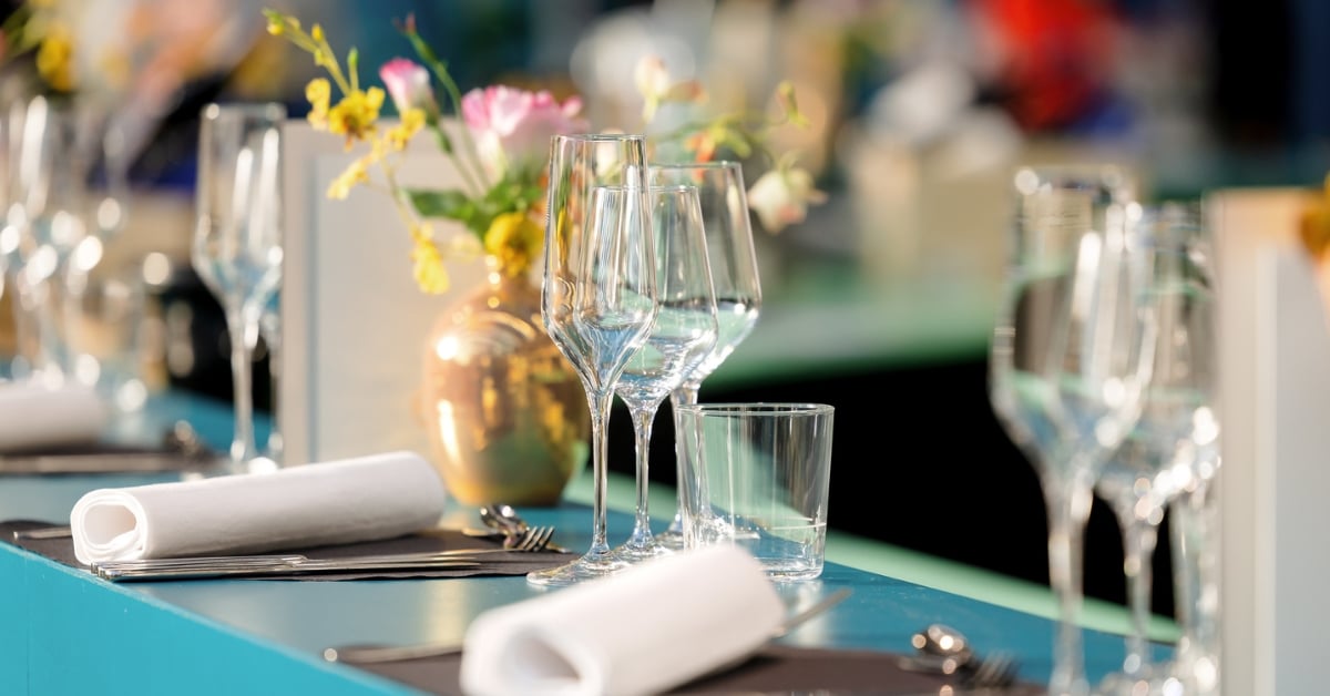 Gedekte tafel met glazen wijn, bestek, servetten en een bloemetje