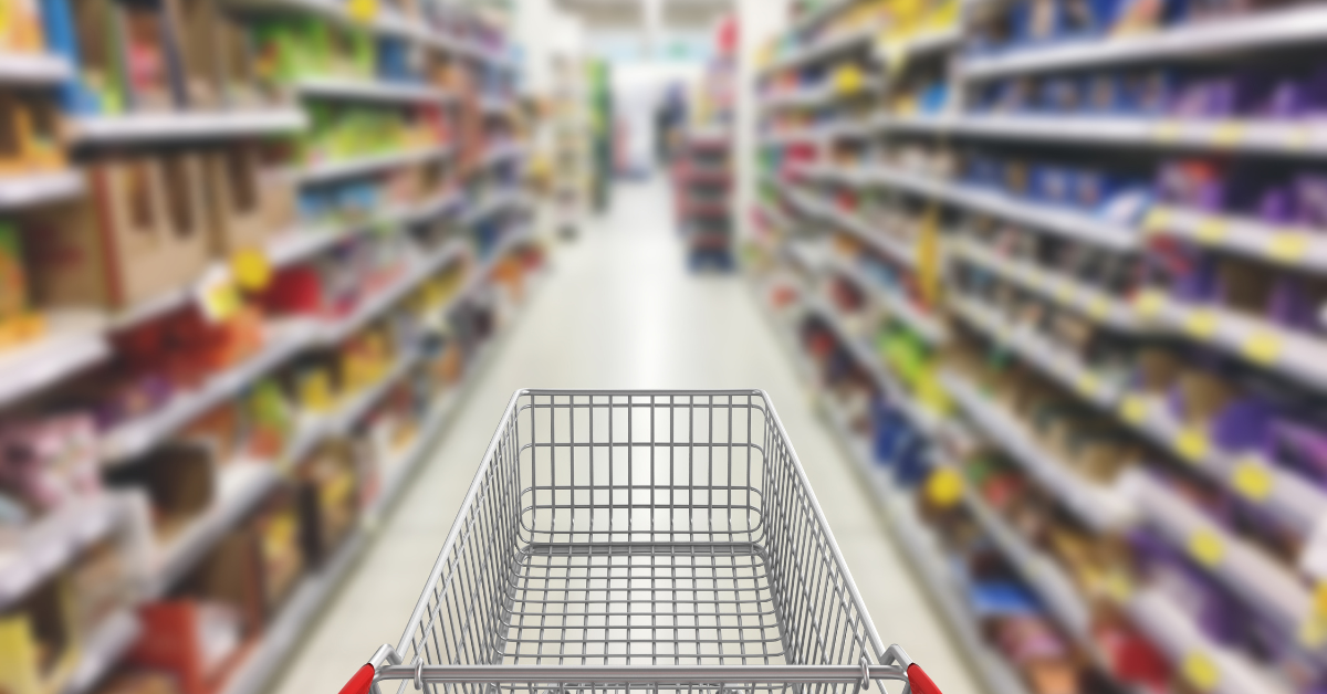 Foto van een winkelkar in het gangpad van een supermarkt. 