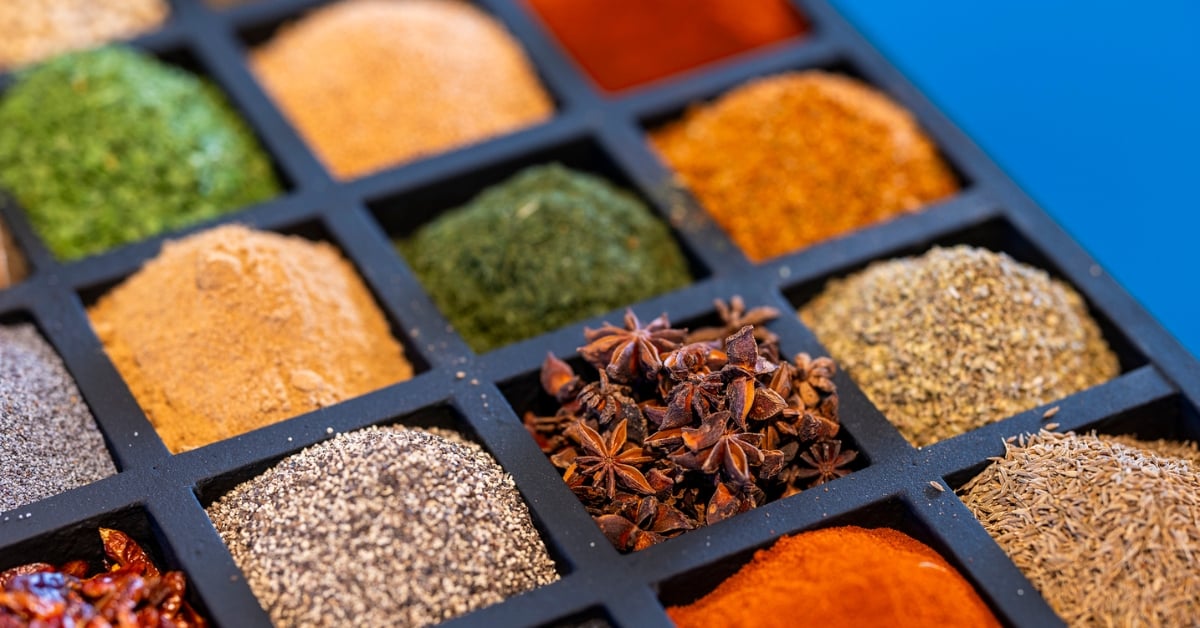 Close-up van kleurrijke kruiden en specerijen in afzonderlijke vakjes, variërend van gemalen specerijen tot steranijs.