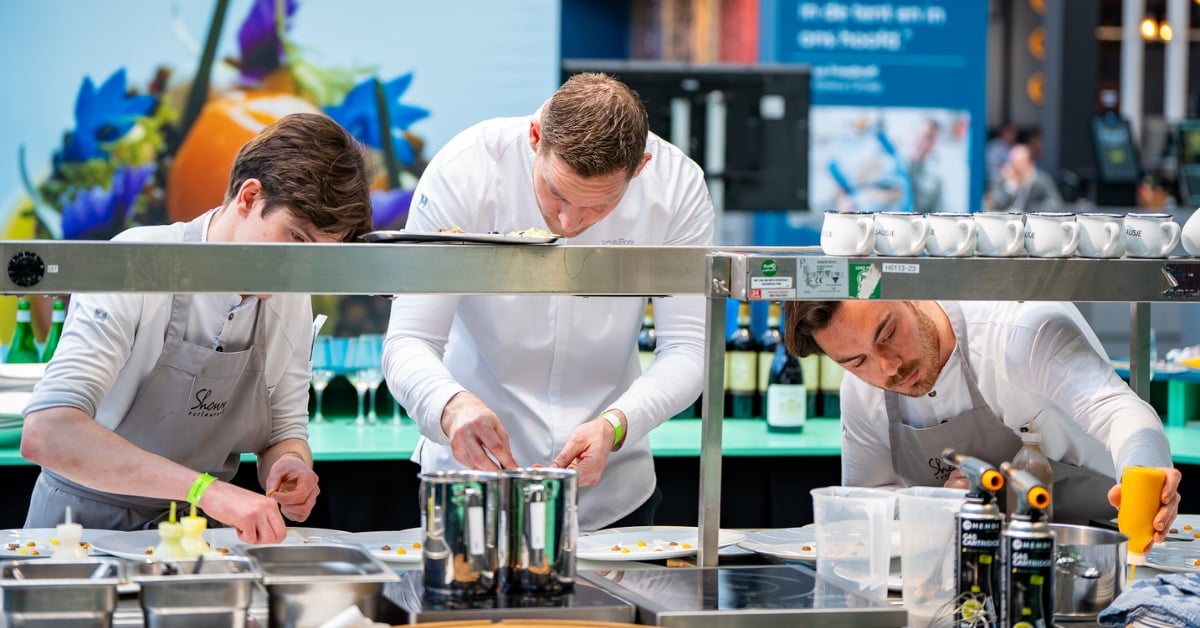 Drie chefs bereiden gerechten zorgvuldig in een horecakeuken