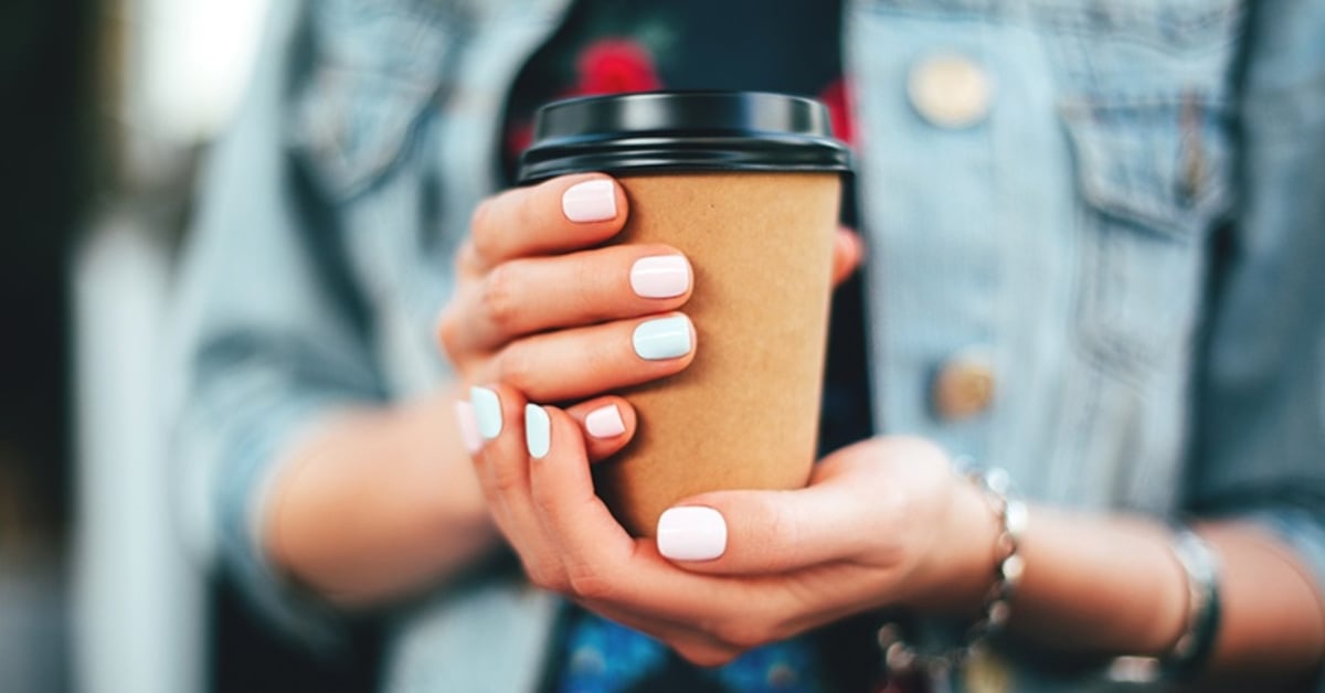 Persoon met to-go koffiebeker in handen