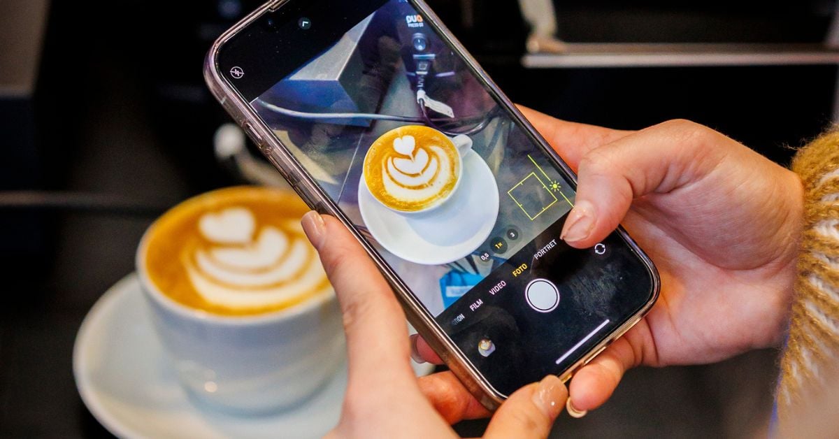 Persoon maakt een foto van een cappuccino met latte art