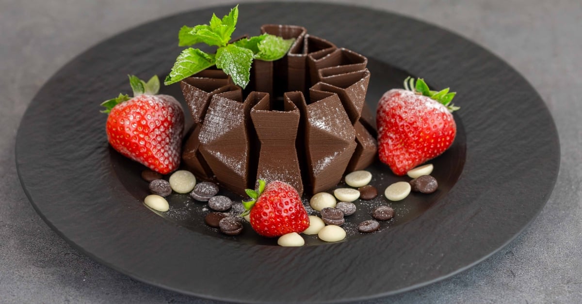 Chocoladedessert 3D-geprint met een Felix Foodprinter, geserveerd met aardbeien en chocoladedruppels.