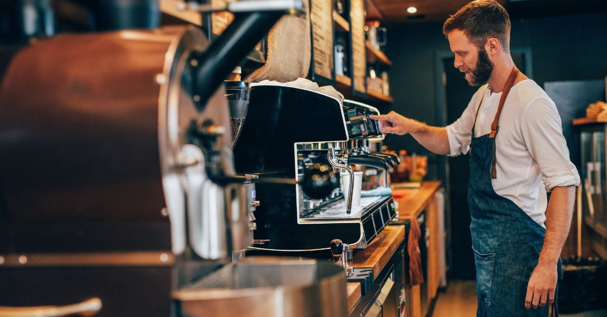 Barista zet koffie met een espressomachine in een sfeervolle koffiebar