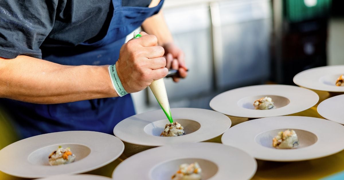 Chef dresseert gerechten op borden met een spuitzak