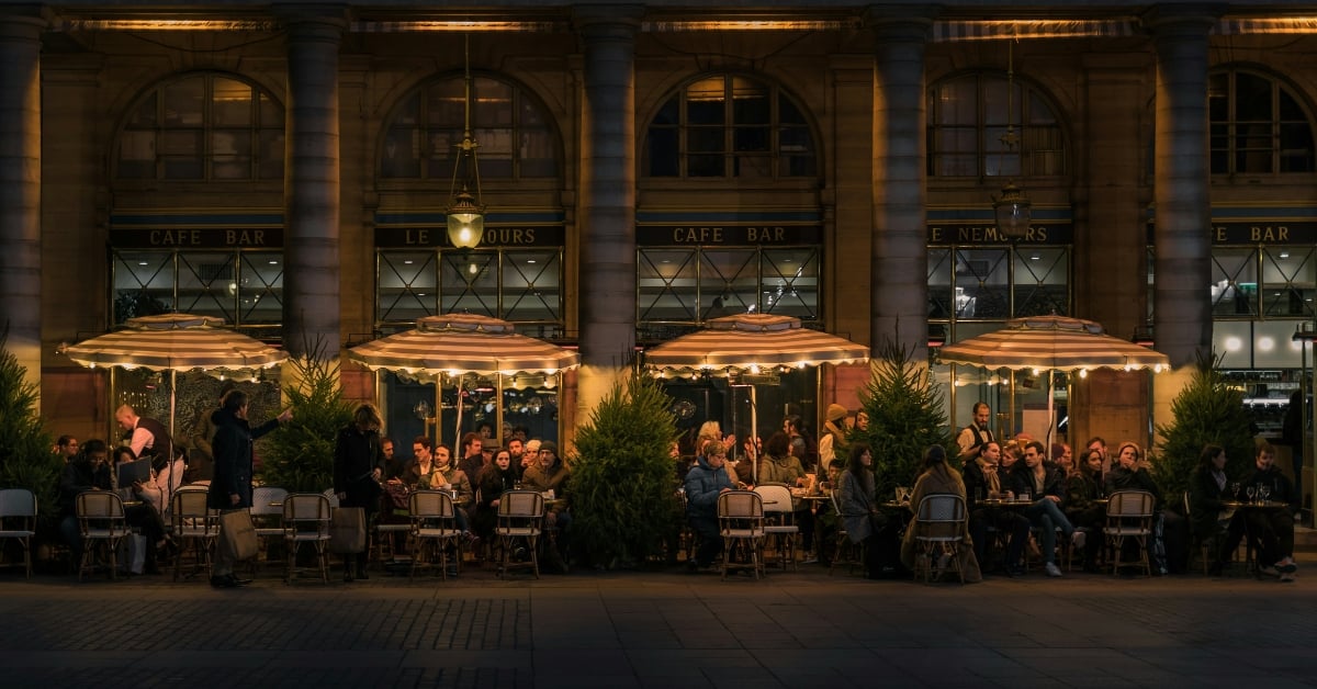 Druk terras van een café in de avond met gasten aan tafels buiten