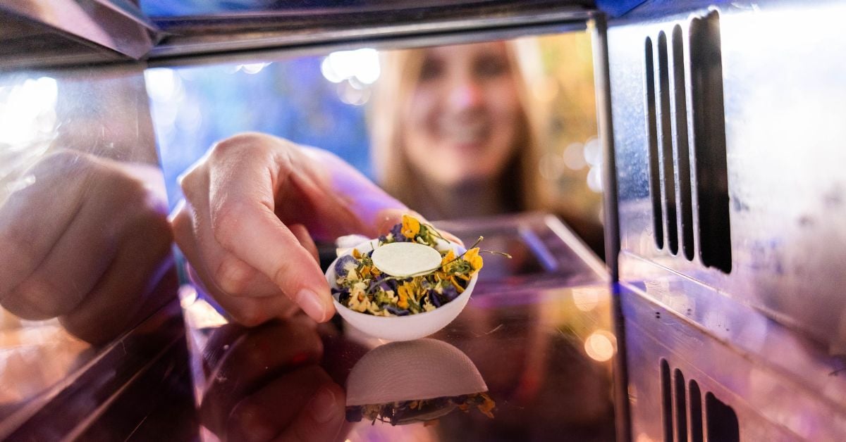 Persoon neemt een klein gerecht uit een food vending-systeem