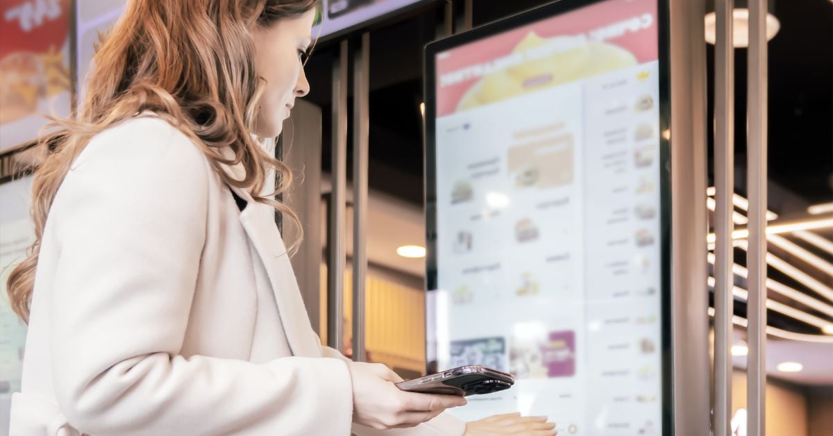 Bezoeker bestelt eten via een digitaal bestelzuil in een fastservicezaak