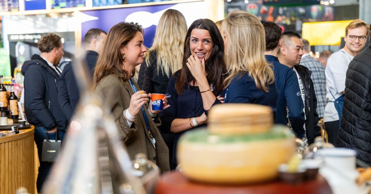 Een groep mensen staat met elkaar te praten en te genieten van een drankje