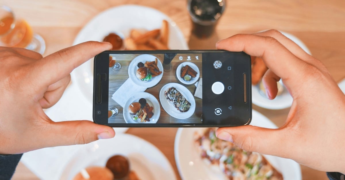 Gast fotografeert gerechten met smartphone in restaurant voor social media
