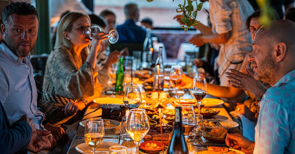 Groep gasten aan tafel in een restaurant die genieten van een shared dining diner met meerdere gerechten om te delen