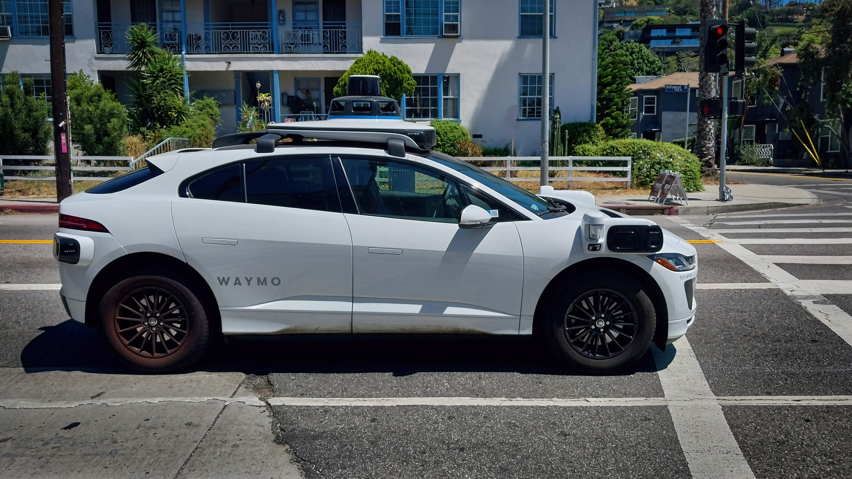 Waymo autonomous electric vehicle stopped at an intersection in a city street setting