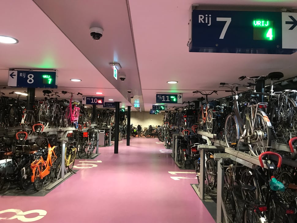 Large Dutch underground bicycle parking in Utrecht with dynamic signs showing available spaces.  Utrecht’s 10,000+ bike parking: digital signage guides riders and delivers valuable usage data.