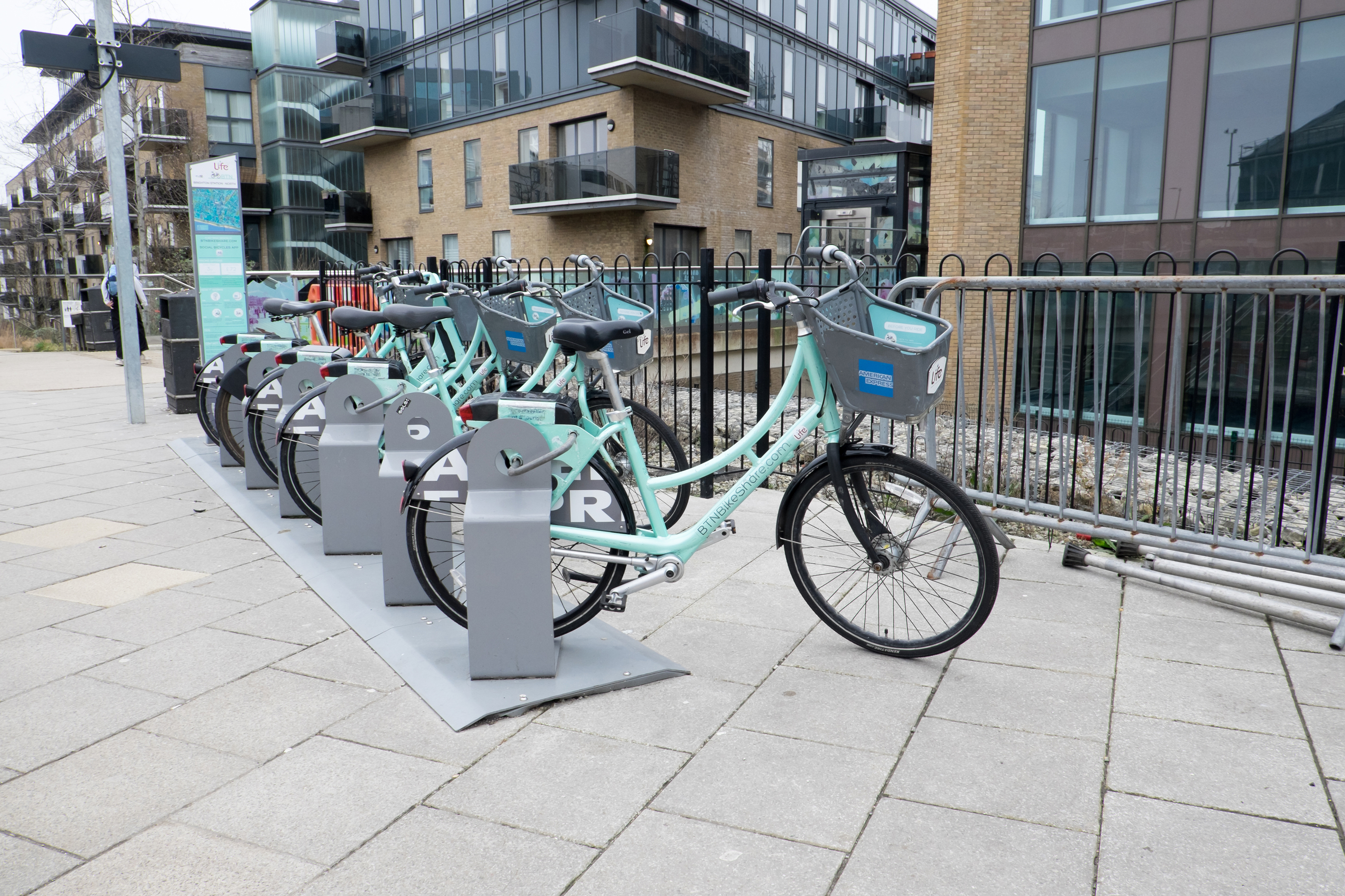 Row of shared bikes neatly parked in a docking station on the sidewalk – organized parking for micromobility.