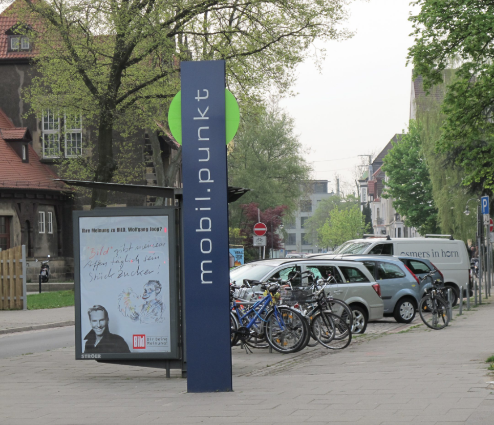 Street-level mobil.punkt in Bremen with bikes and carshare places directly next to parked cars and public transport.