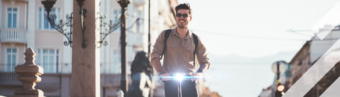 Man riding an electric scooter in a city on a sunny day
