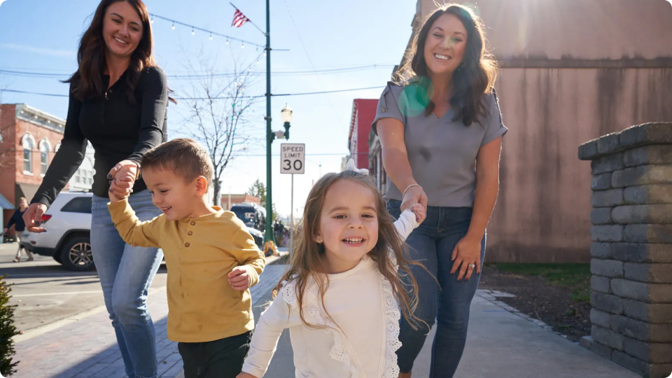 Two mom's and their children walking on a sidewalk together