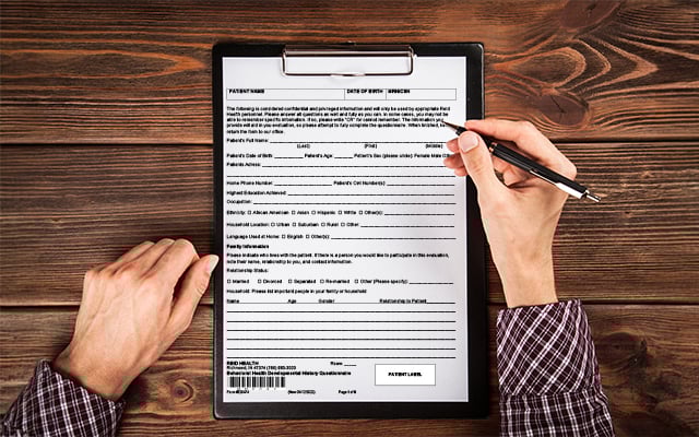 An up close image of the a man's arms holding a pen ready to fill out paperwork